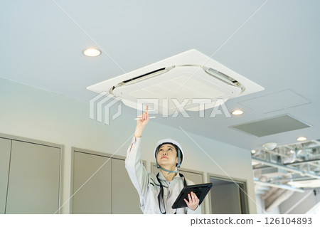 A woman inspecting an air conditioning unit 126104893