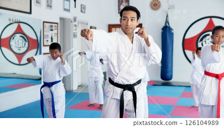 Punch, man and children in karate class, self defense training or martial arts for youth for combat education with sensei. Taekwondo, fight and male instructor with student kids for coaching in dojo 126104989
