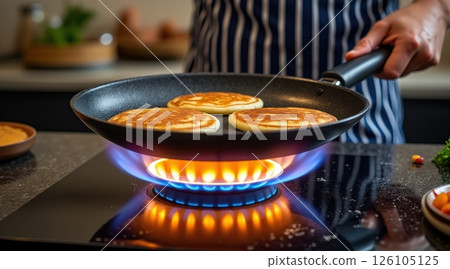 Cooking pancakes in a skillet over a gas flame. 126105125