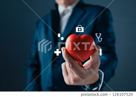 A person in a suit holds a red heart, surrounded by medical icons like a stethoscope, syringe, and cross, symbolizing healthcare, wellness, and the importance of health and medical care. 126107520