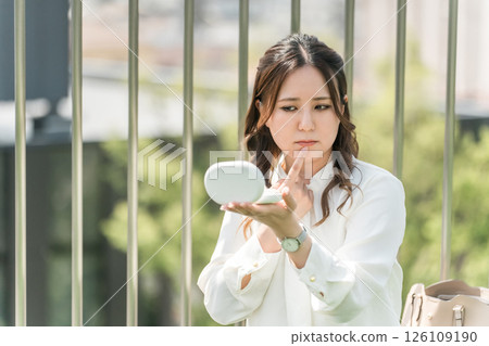 A woman/business woman who retouches her makeup during a break (lipstick, lip rouge, gloss, lips, lips) A woman/business woman who retouches her makeup during a break (lipstick, lip rouge, gloss, lips, lips) 126109190