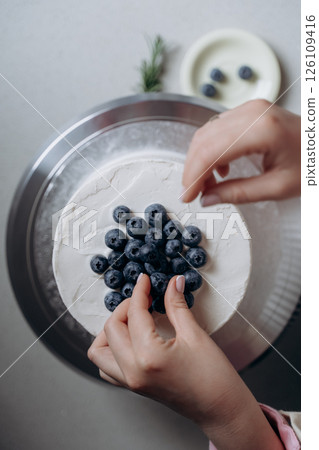 Decorating a Cake with Fresh Blueberries and Cream 126109416