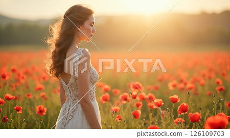 Woman in elegant dress stands in poppy field during sunset, creating a serene moment in nature's beauty 126109703