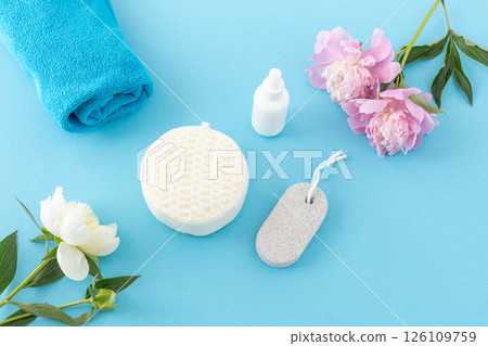 Towel with body care products and peony flowers on the blue background. Towel with body care products and peony flowers on the blue background. 126109759