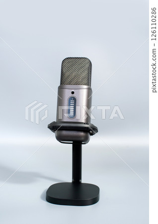 Modern gray microphone on stand against light background Modern gray microphone on stand against light background 126110286