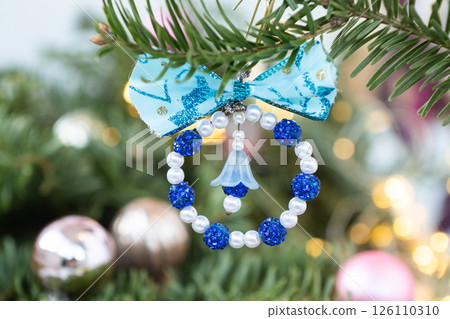 Handmade blue and white beaded christmas ornament hanging on pine tree branch 126110310