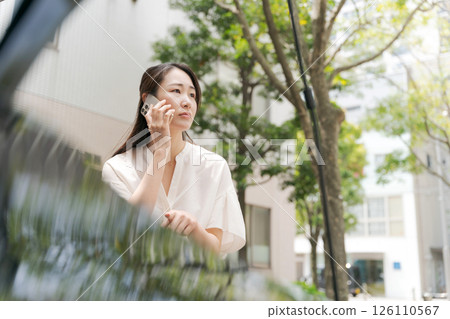 Woman talking on smartphone in front of car 126110567
