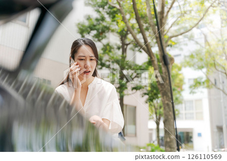 Woman talking on smartphone in front of car 126110569