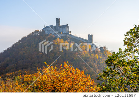 The medieval Bezdez Castle stands majestically atop a hill, surrounded by vibrant autumn foliage. This iconic Gothic structure showcases its historical significance in the Czech landscape. The medieval Bezdez Castle stands majestically atop a hill, surrounded by vibrant autumn foliage. This iconic Gothic structure showcases its historical significance in the Czech landscape. 126111697