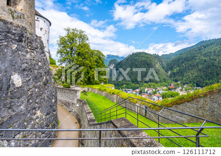 Explore Kufstein Fortress perched on a hill, offering stunning views of the surrounding Tyrol landscape, including green hills, charming villages, and clear blue skies. 126111712