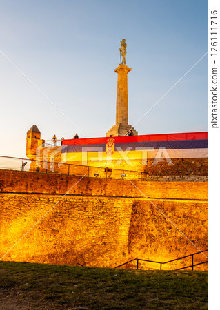 Kalamegdan Fortress showcases the impressive Victor Monument as the evening sky creates a warm, golden atmosphere. Visitors enjoy the historic site, highlighting Serbia's rich heritage. Kalamegdan Fortress showcases the impressive Victor Monument as the evening sky creates a warm, golden atmosphere. Visitors enjoy the historic site, highlighting Serbia's rich heritage. 126111716