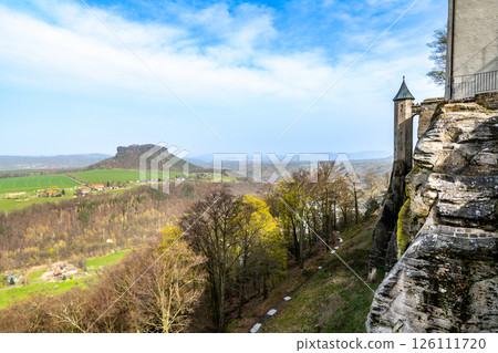 At Konigstein Fortress in Saxony, visitors enjoy stunning panoramic views of rolling hills and lush valleys under a bright blue sky, highlighting the beauty of the German countryside. At Konigstein Fortress in Saxony, visitors enjoy stunning panoramic views of rolling hills and lush valleys under a bright blue sky, highlighting the beauty of the German countryside. 126111720
