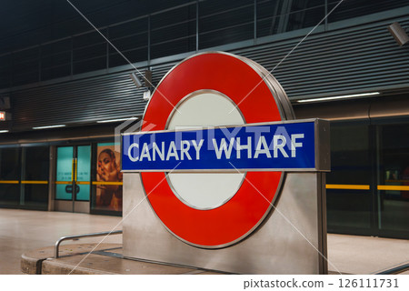 The iconic red and blue London Underground sign at Canary Wharf station, set against a modern interior, captures the essence of urban transit in London. The iconic red and blue London Underground sign at Canary Wharf station, set against a modern interior, captures the essence of urban transit in London. 126111731
