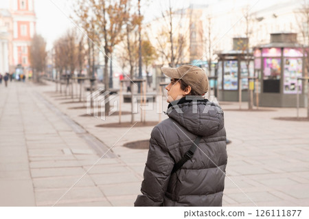young man walking in european quiet city street with trees during a cool autumn day. lifestyle waist up portrait. tourism, date 126111877
