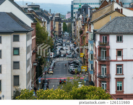 Urban scene in Frankfurt, Germany, featuring European style buildings, parked cars, trees, and distant modern office buildings blending old and new. 126111980