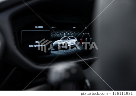 Detailed view of a Lamborghini Urus digital dashboard showing a silver car rendering, speedometer, date, time, temperature, and side light status. 126111981