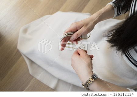 Woman unplugging and organizing phone charging cable 126112134