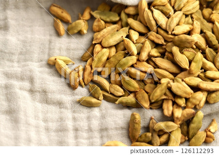 Dried Indian spice cardamom in pods on a cloth napkin close-up Dried Indian spice cardamom in pods on a cloth napkin close-up 126112293