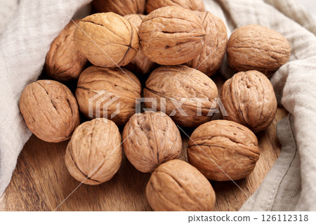 Walnuts on wooden table with crumpled linen cloth napkin.  126112318