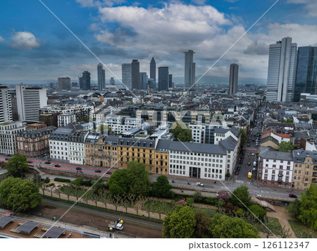 Aerial view of Frankfurt, Germany, featuring the Messeturm skyscraper, modern and historic architecture, tree lined streets, and a park area. 126112347