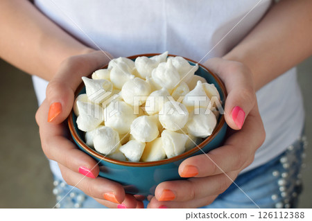 Mini meringues cookies. Homemade Meringue kisses drops in blue bowl in girl hand. Sweet pastry. Gluten free 126112388