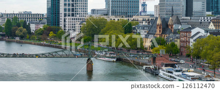 Scenic aerial view of Frankfurt, Germany, featuring the Eiserner Steg, the Main River with docked boats, modern skyscrapers, and historic architecture. Scenic aerial view of Frankfurt, Germany, featuring the Eiserner Steg, the Main River with docked boats, modern skyscrapers, and historic architecture. 126112470