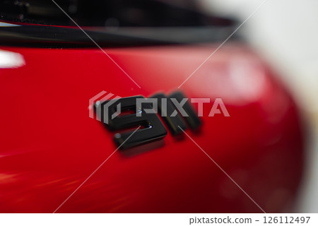 Close up view of the black 911 badge on the rear of a red 2025 Porsche 911 GT3 922. The glossy paint reflects light, with a blurred background. Close up view of the black 911 badge on the rear of a red 2025 Porsche 911 GT3 922. The glossy paint reflects light, with a blurred background. 126112497