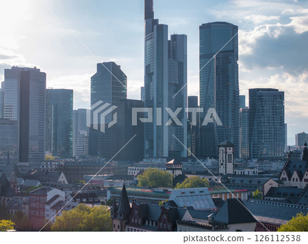 Modern skyscrapers, including Commerzbank Tower, rise above traditional European architecture in Frankfurt, Germany, under a partly cloudy sky. Modern skyscrapers, including Commerzbank Tower, rise above traditional European architecture in Frankfurt, Germany, under a partly cloudy sky. 126112538