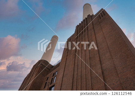 The iconic Battersea Power Station in London features Art Deco architecture, four white chimneys, and a vibrant sky with pink and blue hues. The iconic Battersea Power Station in London features Art Deco architecture, four white chimneys, and a vibrant sky with pink and blue hues. 126112546