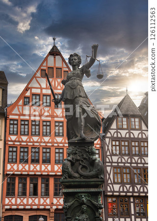 The Fountain of Justice in Frankfurt's Romerberg square, featuring Lady Justice, with colorful half timbered buildings in the background. 126112563