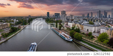 Aerial view of Frankfurt, Germany, showcasing the River Main, modern skyscrapers like Main Tower, historic buildings, and vibrant sunset hues. Aerial view of Frankfurt, Germany, showcasing the River Main, modern skyscrapers like Main Tower, historic buildings, and vibrant sunset hues. 126112592