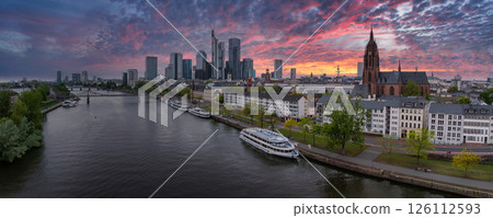Aerial view of Frankfurt, Germany, at sunset featuring modern skyscrapers, the Commerzbank Tower, Frankfurt Cathedral, Main River, and Eiserner Steg bridge. 126112593