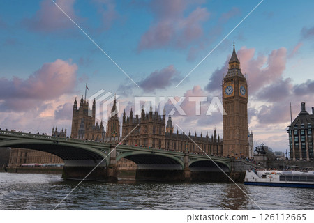 The Palace of Westminster and Elizabeth Tower, with Westminster Bridge over the River Thames, set against a pink and blue evening sky in London. 126112665