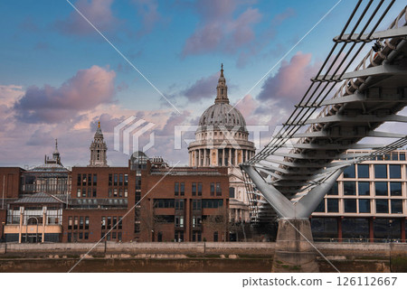 St. Paul's Cathedral's dome stands out against a colorful sky, with the Millennium Bridge to the right and urban buildings along the Thames River in view. St. Paul's Cathedral's dome stands out against a colorful sky, with the Millennium Bridge to the right and urban buildings along the Thames River in view. 126112667