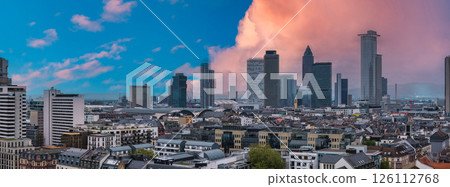 Aerial view of Frankfurt, Germany, featuring modern skyscrapers, traditional architecture, and the Hauptbahnhof under a vibrant sunset sky. Aerial view of Frankfurt, Germany, featuring modern skyscrapers, traditional architecture, and the Hauptbahnhof under a vibrant sunset sky. 126112768