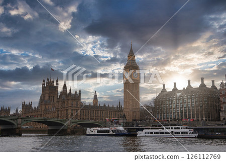 Big Ben and the Palace of Westminster stand by the River Thames in London. Westminster Bridge crosses the river, with boats docked nearby. Big Ben and the Palace of Westminster stand by the River Thames in London. Westminster Bridge crosses the river, with boats docked nearby. 126112769