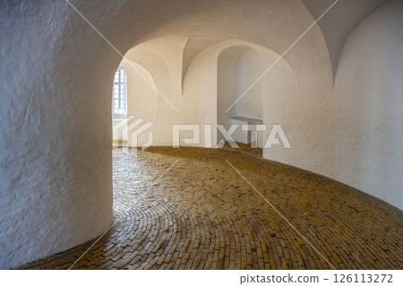 Visitors explore the winding, wooden-floored spiral ramp of Round Tower in Copenhagen. This historic structure offers unique architectural elements and stunning views from the top. Visitors explore the winding, wooden-floored spiral ramp of Round Tower in Copenhagen. This historic structure offers unique architectural elements and stunning views from the top. 126113272