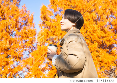Woman drinking a hot drink while enjoying the autumn leaves Lifestyle image Woman drinking a hot drink while enjoying the autumn leaves Lifestyle image 126113328