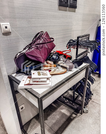 Assorted footwear and handbag cluttered on table in retail space with clothing rack nearby. High quality photo Assorted footwear and handbag cluttered on table in retail space with clothing rack nearby. High quality photo 126113560