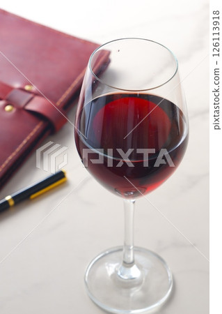 喝著紅酒在酒紅色皮革筆記本上寫日記的圖片 喝著紅酒在酒紅色皮革筆記本上寫日記的圖片 126113918