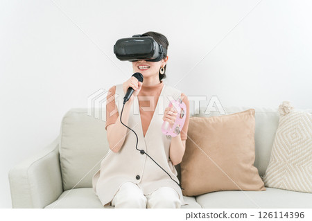 Asian woman wearing VR goggles enjoying karaoke metaverse at home Asian woman wearing VR goggles enjoying karaoke metaverse at home 126114396