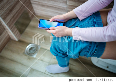 Relaxing moment while scrolling through a phone in the bathroom Relaxing moment while scrolling through a phone in the bathroom 126114549