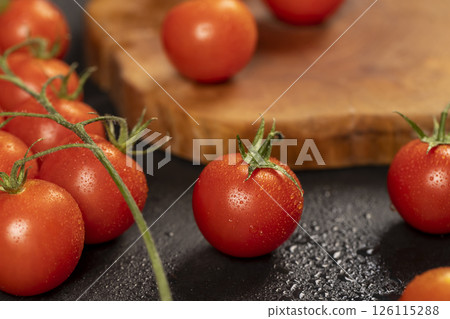 wet ripe small red tomatoes, several red round cherry tomatoes on the table , close up 126115288