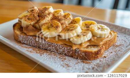 Healthy breakfast featuring banana slices on creamy peanut butter toast. Fresh, natural ingredients create a simple yet delicious morning meal in rustic style. 126117029