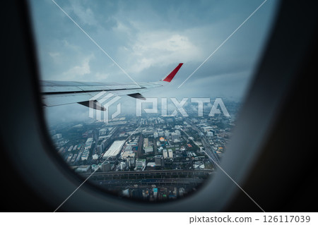 View from airplane window and airplane wing with city view on rainy day. Air travel and tourism. 126117039