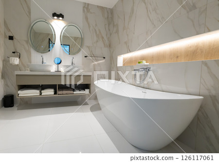 A modern elegant hotel bathroom with freestanding tub, double sink and stylish round mirrors A modern elegant hotel bathroom with freestanding tub, double sink and stylish round mirrors 126117061