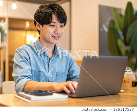 Man using a computer in a cafe 126117537
