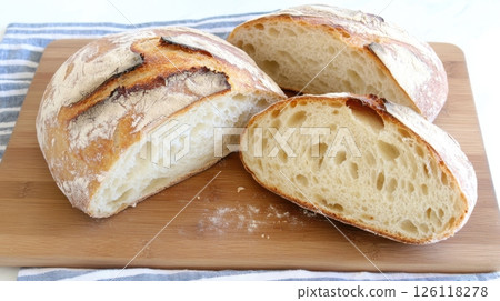 Sourdough bread sliced on a wooden board with visible porous crumb and flour dust in cozy kitchen atmosphere, perfect for artisan food and baking content. 126118278