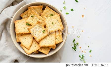 Sourdough crackers arranged in a ceramic bowl with herbs and sea salt, linen napkin, soft shadows, minimal rustic style, zero waste snack concept 126118285