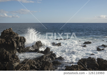 Waves Crashing Against black Lava Rocks on a Tropical Coast, water splashing at canary island Tenerife Waves Crashing Against black Lava Rocks on a Tropical Coast, water splashing at canary island Tenerife 126118960